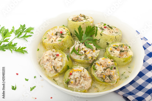 Stuffed zucchini with rice, minced meat and vegetables in white bowl. Decorated with dill, parsley and red pepper.