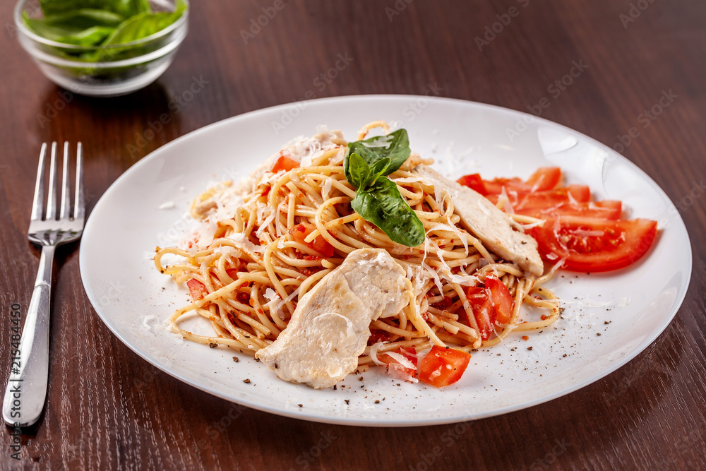 Italian pasta spaghetti with red tomato sauce, tomatoes and grilled chicken. It is on the table in the restaurant. Copy space, selective focus Italian pasta spaghetti with red tomato sauce, tomatoes and grilled chicken. It is on the table in the restaurant. Copy space, selective focus