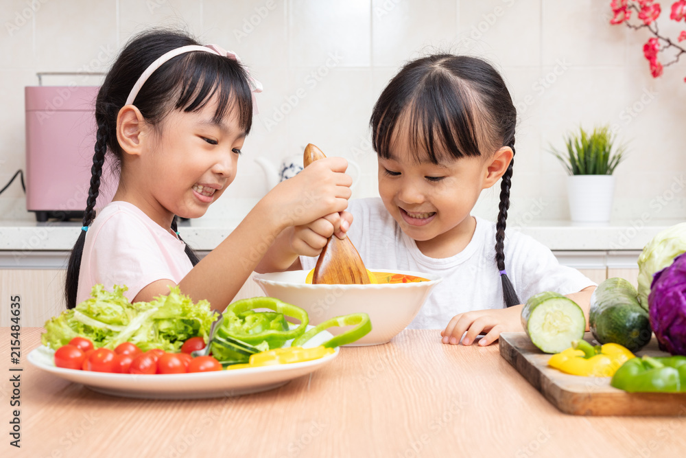 Asian Chinese little sisters making salad in the kitchen Asian Chinese little sisters making salad in the kitchen