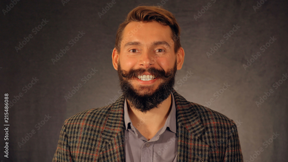 Obraz premium Bearded guy with a beautiful smile looks at the camera