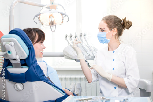 Dentist in a white coat wearing gloves preparing to work with clients