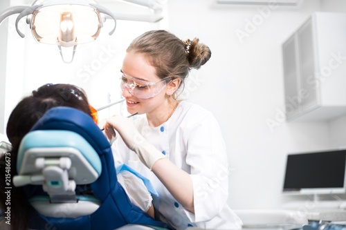 Beautiful girl dentist treats teeth to customers