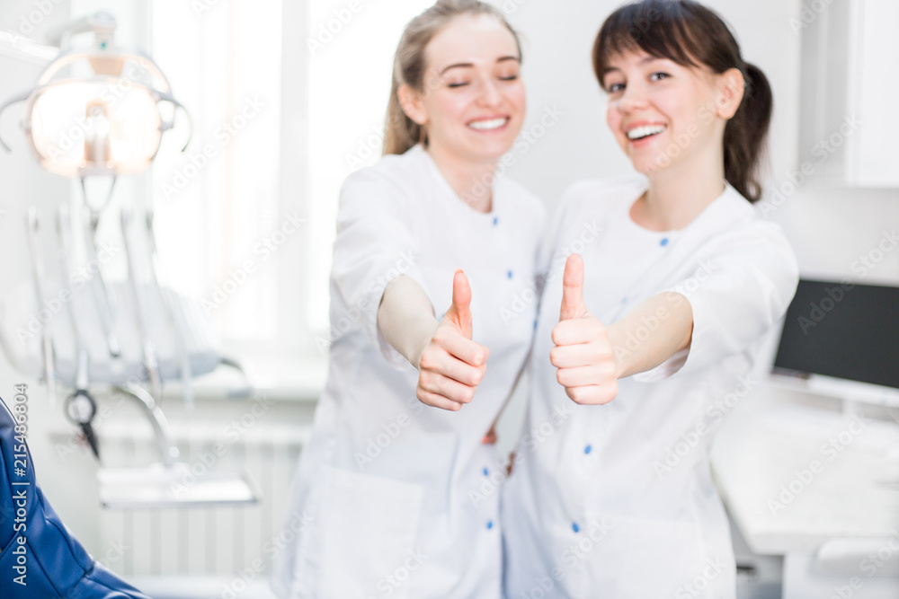Obraz premium Girls dentists in uniform in the dental Department show hands class lifting the thumb up