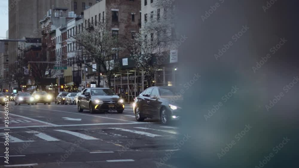 Busy downtown New York intersection with afternoon city with a bunch of yellow cab taxis passing by and cherry trees blooming in the background