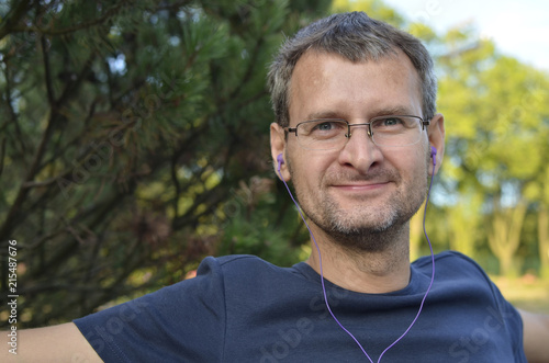 A close-up of a man with headphones in the open air