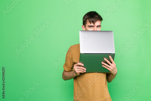 Young guy covered his face partially with a laptop hiding data