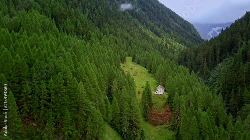 Droneflight away from a small chapel in idyllic forest hidden somewhere in swiss mountains.