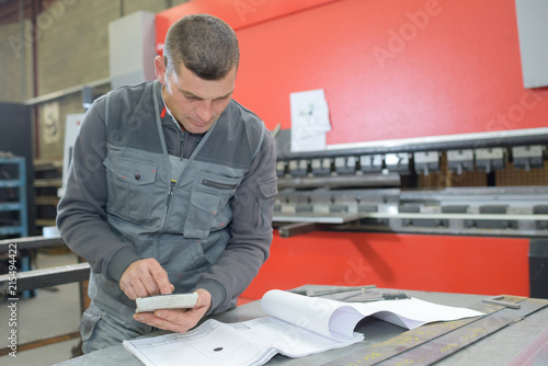 Workman looking at paperwork and using calculator photo