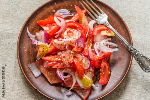 Delicious simple salad of tomato and red onion on a rustic pottery plate