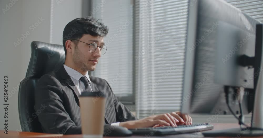 Young positive turkish businessman working at his computer on project and smiling, business concept 4k Young positive turkish businessman working at his computer on project and smiling, business concept 4k