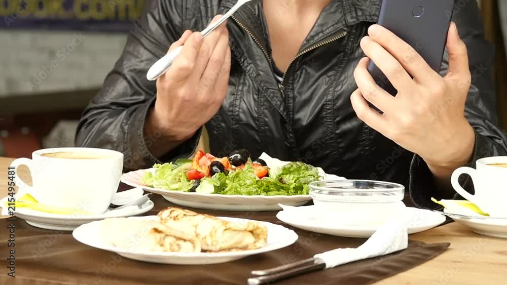 lunch in an outdoor cafe. businesswoman eating salad and checks email on your phone. slow motion lunch in an outdoor cafe. businesswoman eating salad and checks email on your phone. slow motion