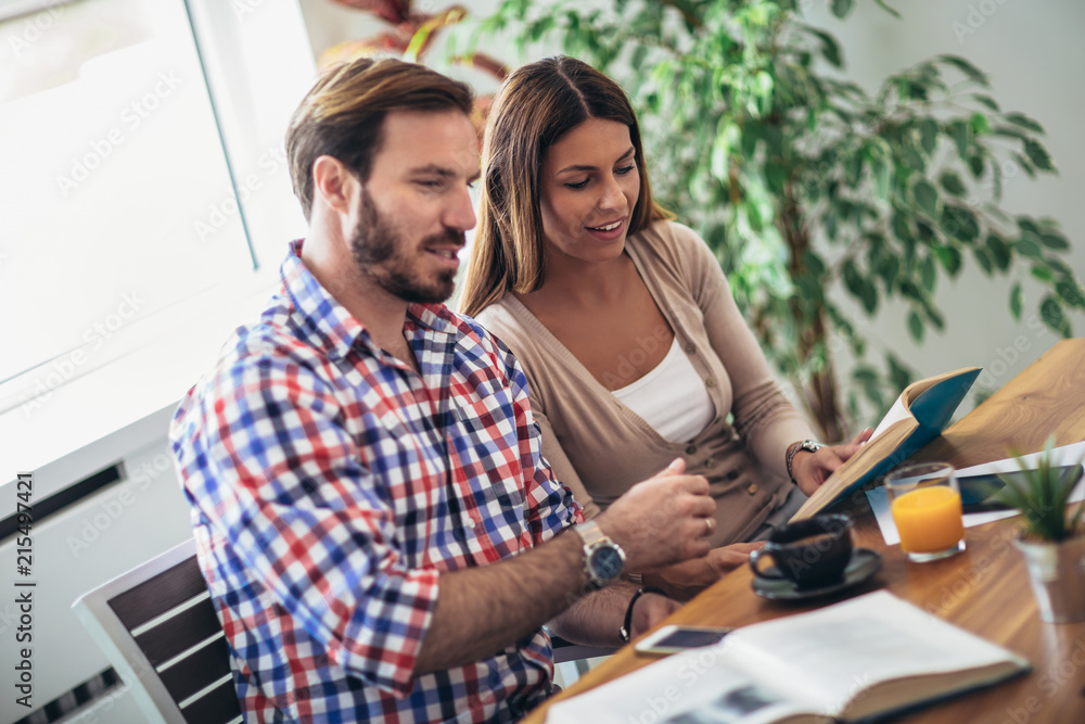 Obraz premium Two students doing homework together and helping each other sitting in a table at home with a homey background