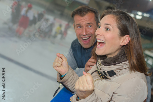 Excited couple cheering on ice hockey team