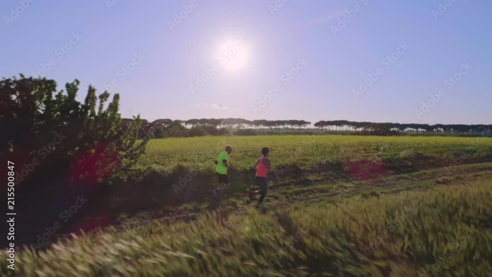 Young couple jogging in the countryside near the forest at sunset Young couple jogging in the countryside near the forest at sunset