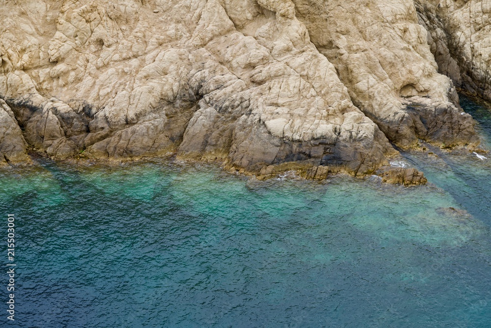beige rocks ending in a turquoise sea