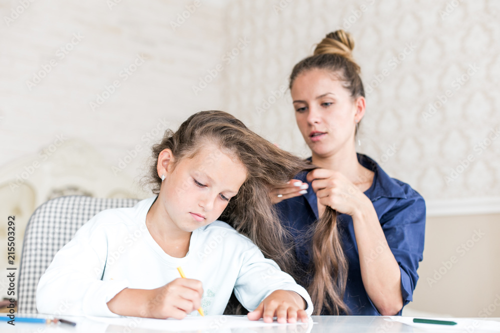 Happy loving family. Mother and daughter are doing hair. dreamy kid girl drawing and paint with color pencils
