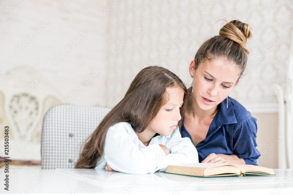 happy family mother and daughter read a book in the evening at home. the concept of family comfort and family relations happy family mother and daughter read a book in the evening at home. the concept of family comfort and family relations
