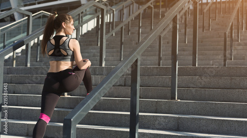 Attractive young sporty woman stretching on stairs