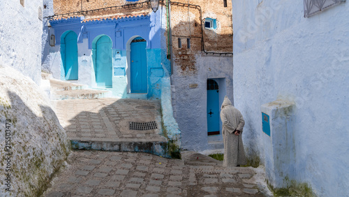 Unidentified man walking in blue medina of Chefchaouen city in Morocco, North Africa © CanYalicn