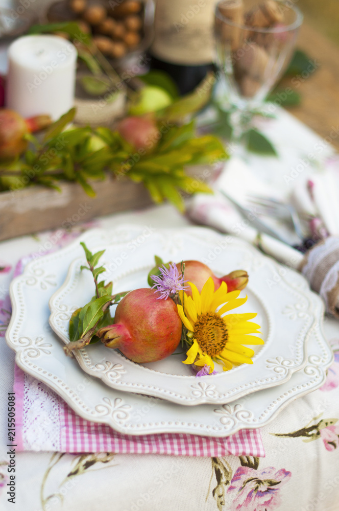 Romantic dinner in the autumn garden, table setting for a nice dinner. Wine, fruit, pomegranate and flowers. Picnic in the open air Romantic dinner in the autumn garden, table setting for a nice dinner. Wine, fruit, pomegranate and flowers. Picnic in the open air