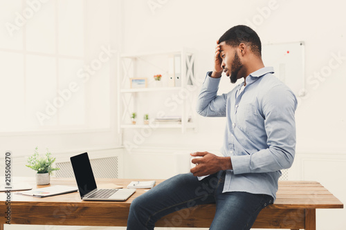 Surprised black businessman looking at laptop