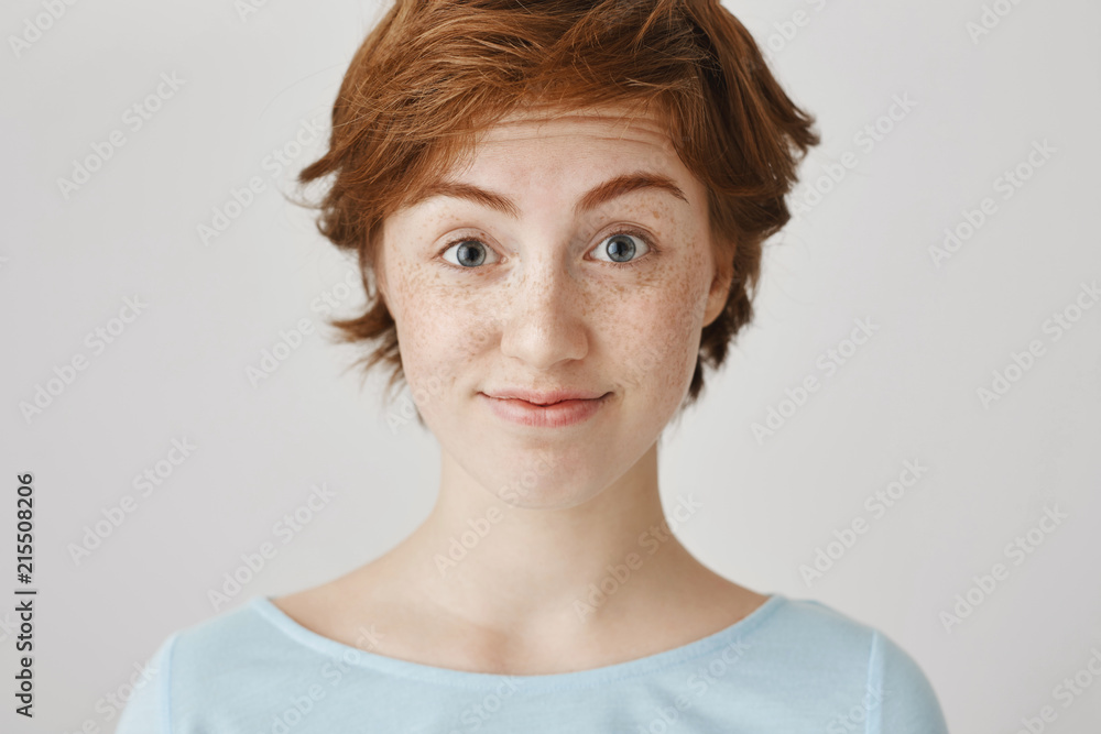 I doubt your idea. Close-up portrait of attractive caucasian redhead with freckles lifting eyebrows, hesitating, smiling anxiously, standing over gray background. Are you seriously going to wear that I doubt your idea. Close-up portrait of attractive caucasian redhead with freckles lifting eyebrows, hesitating, smiling anxiously, standing over gray background. Are you seriously going to wear that