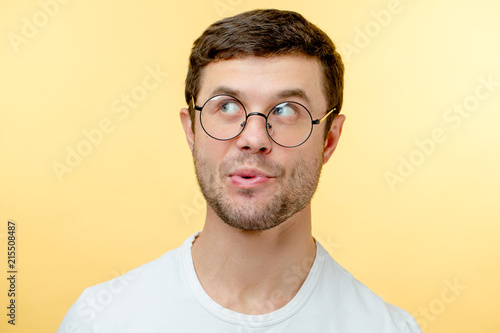 pleasant young man in glasses whistling a song. guy with interesting expression. look up. indifference concept