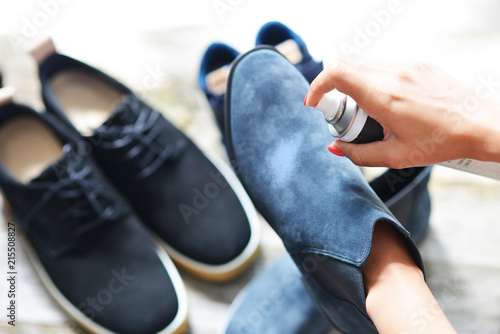 Shoes care concept with woman hands spraying leather shoe
