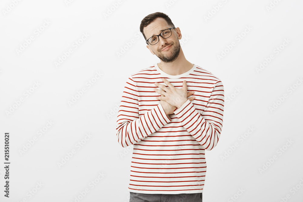 Oh it is so sweet. Portrait of cute pleased gay boyfriend in glasses, standing touched over gray background, tilting head and smiling, holding hands on heart after confession that melt heart Oh it is so sweet. Portrait of cute pleased gay boyfriend in glasses, standing touched over gray background, tilting head and smiling, holding hands on heart after confession that melt heart