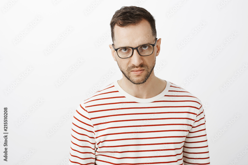 I hate you. Portrait of pissed off angry adult european who expressing disdain and anger, looking from under forehead and frowning, being annoyed and standing over gray background with contempt I hate you. Portrait of pissed off angry adult european who expressing disdain and anger, looking from under forehead and frowning, being annoyed and standing over gray background with contempt