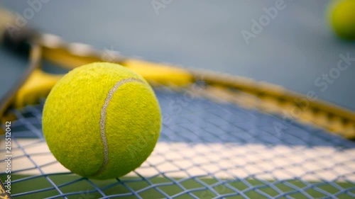 Close up of tennis equipment on the court. Sport, recreation concept. Yellow racket with a tennis ball in motion on a clay green blue court next to the white line with copy space and soft focus. photo