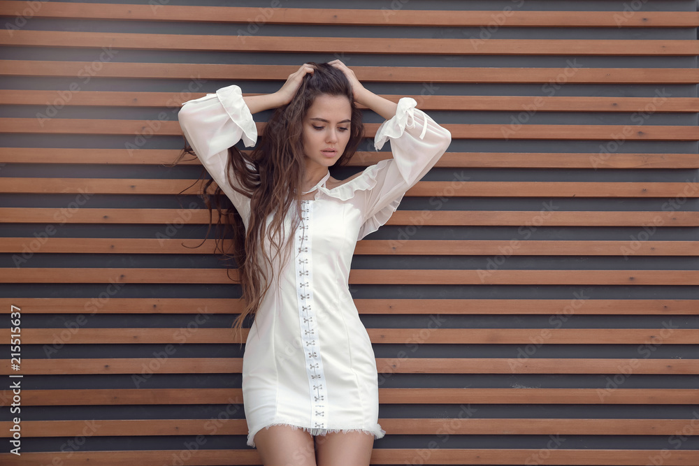 Sexy young brunette girl in white short dress against wooden strip wall, fashion  style outdoor shot. Stock Photo | Adobe Stock