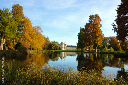View of Chantilly castle reflected in pool surrounded by park trees. Autumn. France.