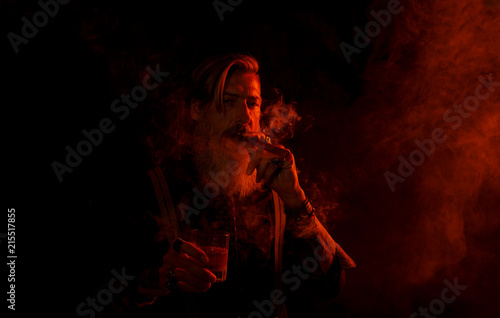 Portrait eines bärtigen rauchenden Mannes mit rotem Licht und dunklem Hintergrund
