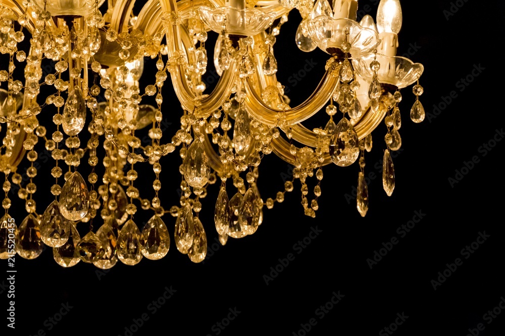 Luxury chandelier with light candles and right dark background. Noble candelabra hanging on ceiling with lots of little gems Luxury chandelier with light candles and right dark background. Noble candelabra hanging on ceiling with lots of little gems