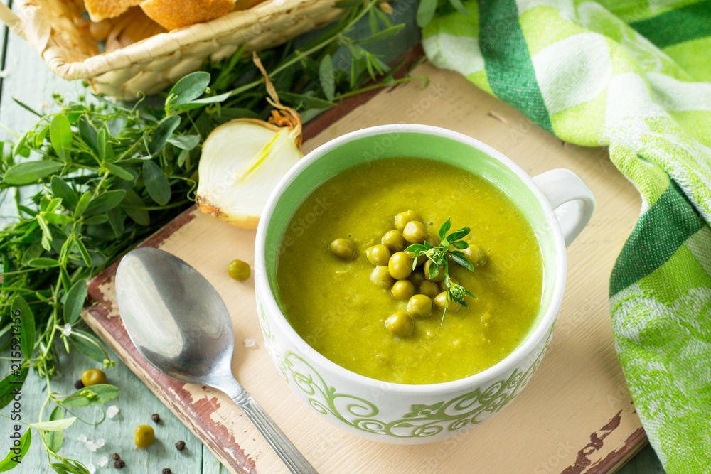 Puree soup with green pea in a bowl on a kitchen wooden table. The concept of healthy eating. Diet menu. Copy space. Puree soup with green pea in a bowl on a kitchen wooden table. The concept of healthy eating. Diet menu. Copy space.