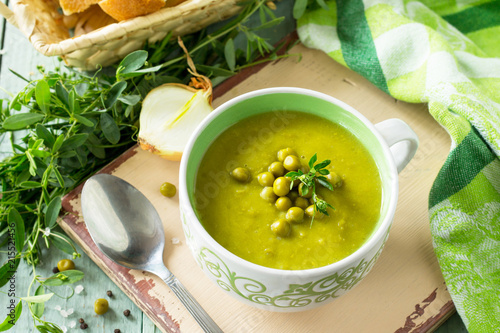 Puree soup with green pea in a bowl on a kitchen wooden table. The concept of healthy eating. Diet menu. Copy space.