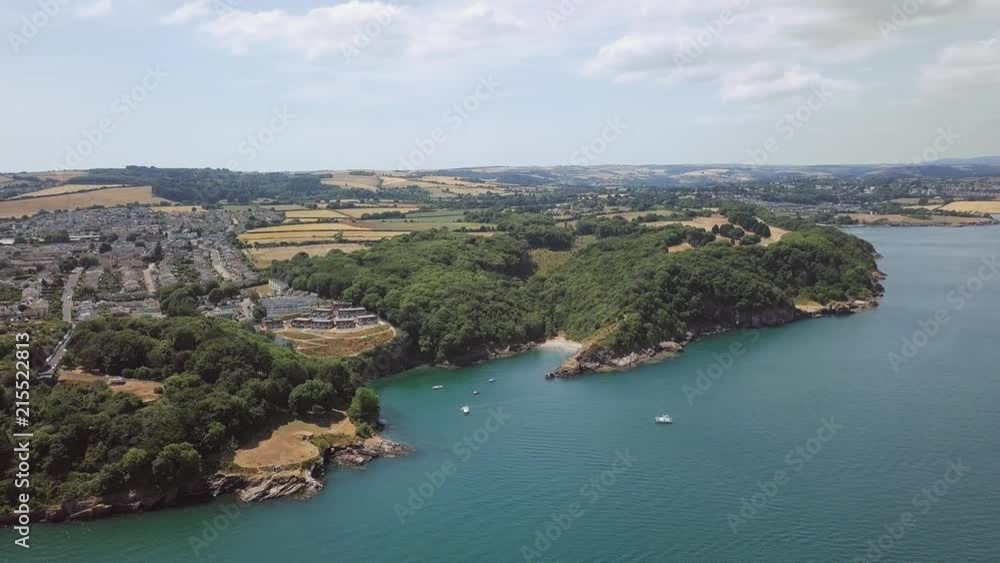 Panorama sky view of beach in Brixham England. Flying over coastal town with harbour and lighthouse.