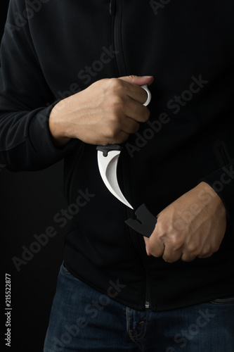 combat and violence concept, a man pulling out a karambit knife