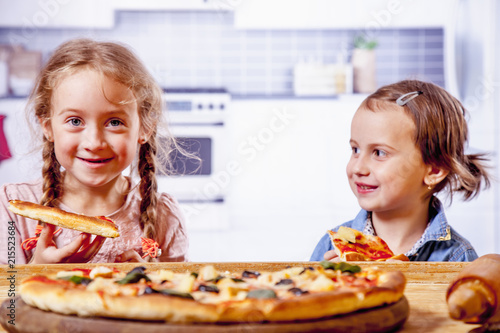 Children love to eat pizza. Cute little girls best friends eating pizza.