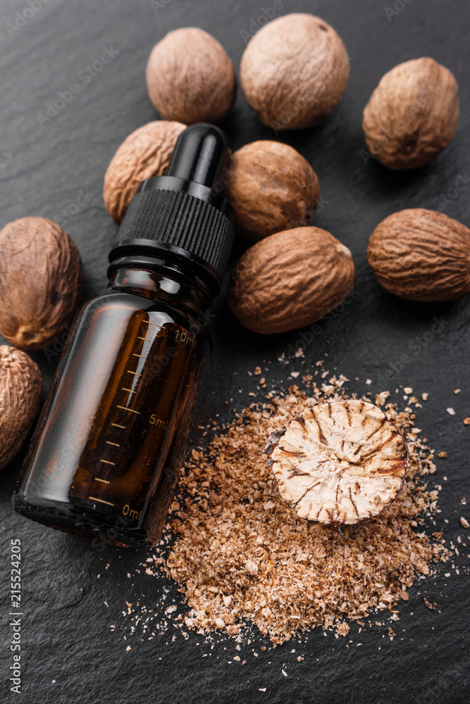 nutmeg essential oil on a dark stone background nutmeg essential oil on a dark stone background