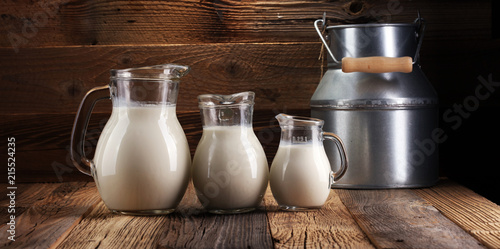 A jug of milk and glass of milk on a wooden table