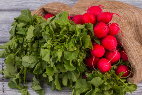 Raw radishes with green leaves. Close up. Grey wooden table background.
