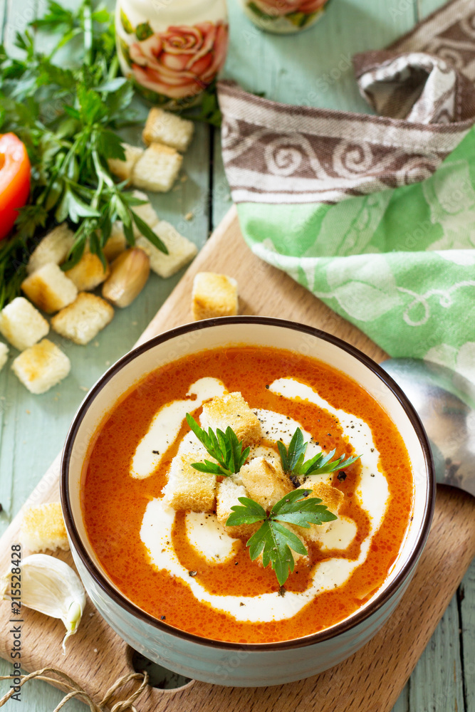 Puree soup tomato with croutons and cream in a bowl on on a kitchen wooden table. The concept of healthy eating. Diet menu. Copy space. Puree soup tomato with croutons and cream in a bowl on on a kitchen wooden table. The concept of healthy eating. Diet menu. Copy space.