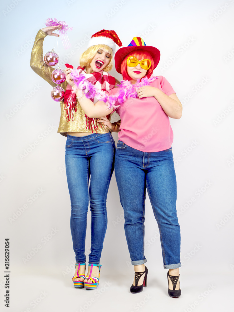 Bright fashion portrait of pretty young best friends celebrating Christmas party, having great party time. Sisters spending new year holidays together on a light background Bright fashion portrait of pretty young best friends celebrating Christmas party, having great party time. Sisters spending new year holidays together on a light background