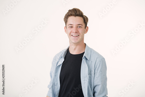 Friendly looking handsome young man wearing blue shirt smiling standing over white background