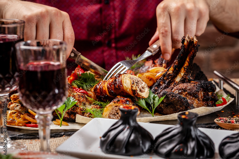 Traditional Georgian and Armenian cuisine. A man holds a knife and a fork in his hands, and there is meat cooked on a grill in a Georgian restaurant. Copy space, selective focus