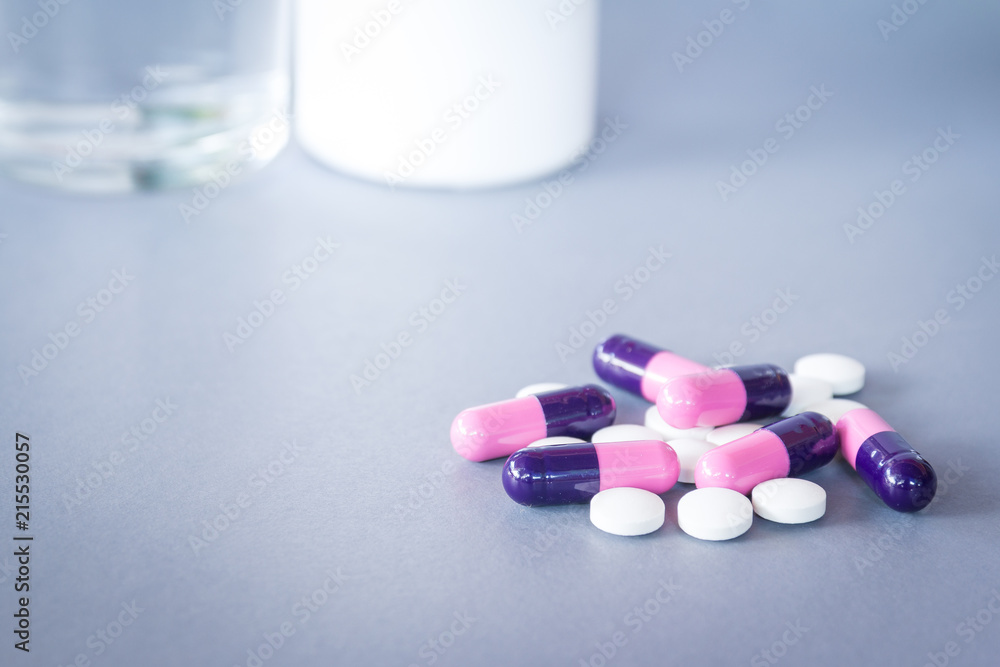 pills and tablets on grey background with bottle and glass pills and tablets on grey background with bottle and glass