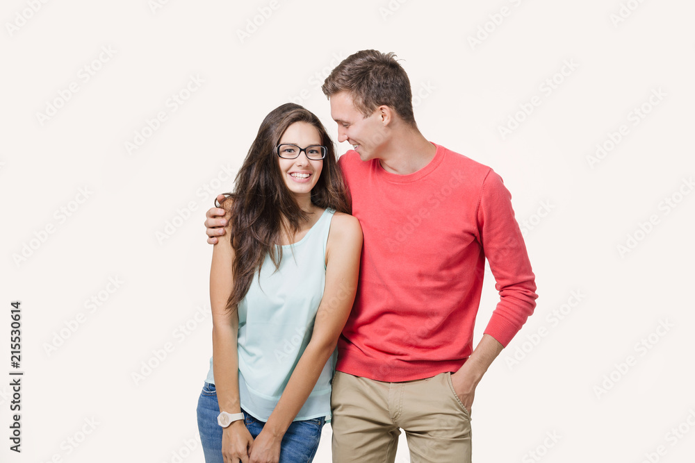 Happy young lovely couple standing together and laughing. Studio shot over white background. Friendship, love and relationships concept