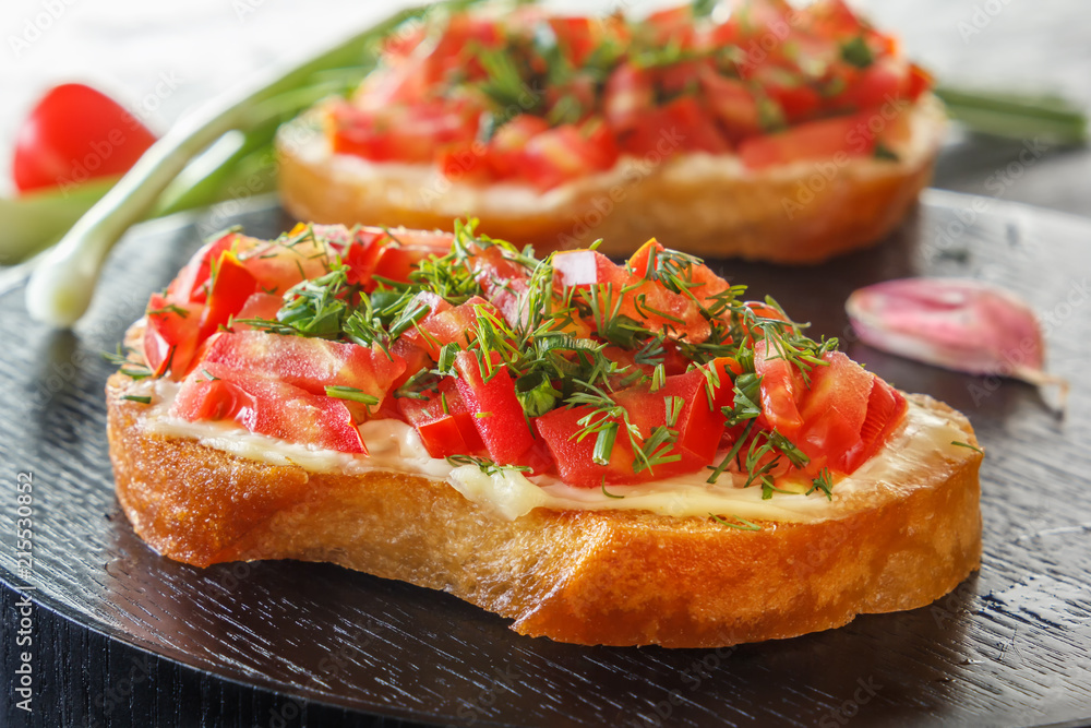 Bruschetta with fresh tomatoes and cheese on a black plate. Close-up